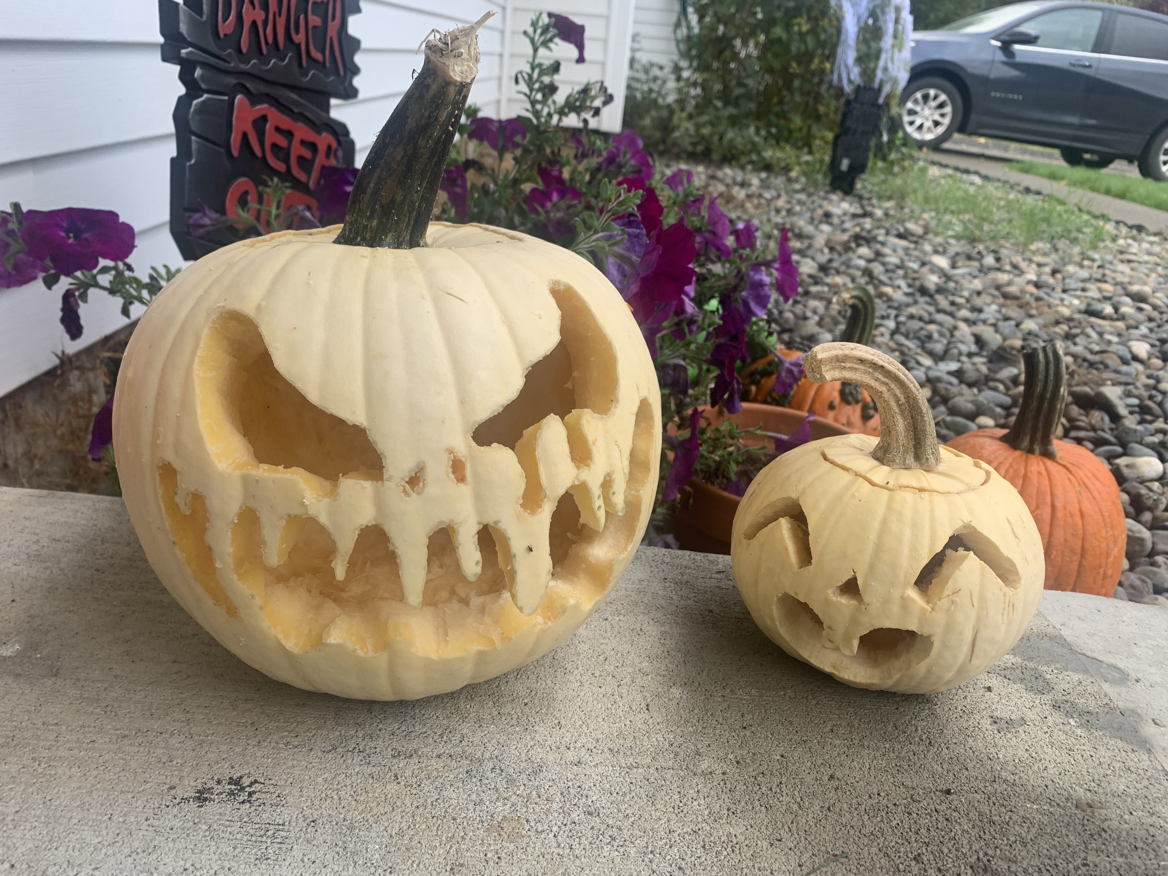 Two carved jack-o-lanterns. One has a scary face and one has a happy face. The scary one is larger than the cute one.